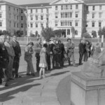 On Anzac Day in 1973 there was wreath laying by a number of countries at the Wellington Cenotaph. After the main ceremony a wreath was laid at the Wellington Cenotaph on behalf of the Victoria University Students Association. In this photo supporters of VUWSA listen.