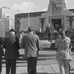 On Anzac Day in 1973 there was wreath laying by a number of countries at the Wellington Cenotaph. After the main ceremony a wreath was laid at the Wellington Cenotaph on behalf of the Victoria University Students Association. In this photo supporters of VUWSA listen to George Goddard..