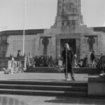 On Anzac Day in 1973 there was wreath laying by a number of countries at the Wellington Cenotaph. After the main ceremony a wreath was laid at the Wellington Cenotaph on behalf of the Victoria University Students Association. Peter Wilson, President of VUWSA addresses the crowd.