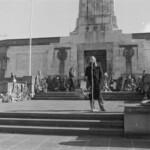 On Anzac Day in 1973 there was wreath laying by a number of countries at the Wellington Cenotaph. After the main ceremony a wreath was laid at the Wellington Cenotaph on behalf of the Victoria University Students Association. Peter Wilson, President of VUWSA addresses the crowd. George Goddard on his left.